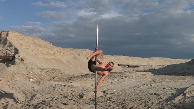 Man trains on a pylon for dancing, he prepares for a show.
