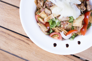 Salad with tomato, mozzarella, and meat on white plate close up. Served restaurant table. Delicious meal at a luxury restaurant.