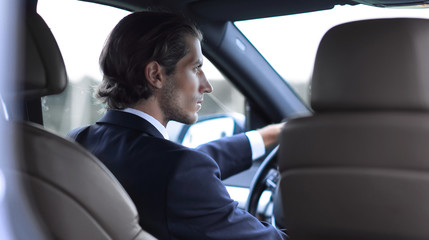 successful man sitting behind the wheel of a car