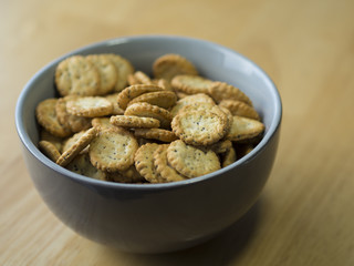 close up poppy seed sesame crunchy crackers in gray bowl on wooden table