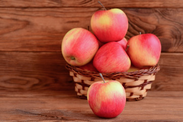 Fresh red apples on a wooden table and in a basket. Brown wooden background with copy space for text. Apples photo. Healthy dessert. Source of pectin and iron