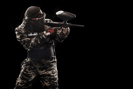 Heavily armed masked soldier isolated on black background. Paint ball and laser tag sport games.