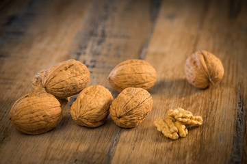 Walnut kernels and whole walnuts on rustic old oak table