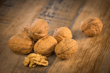 Walnut kernels and whole walnuts on rustic old oak table