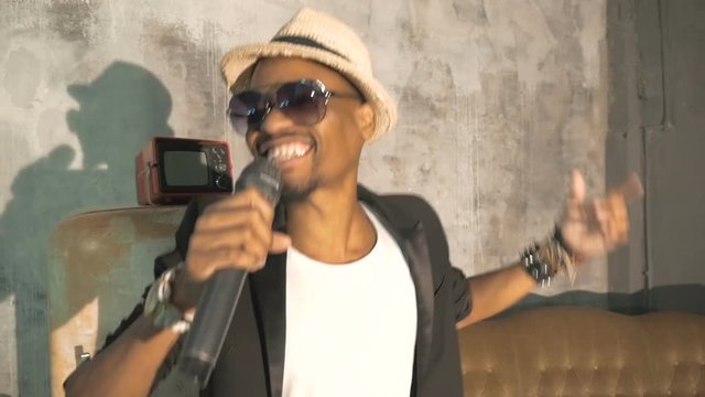 An African man is singing into the microphone. Record a music video.