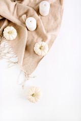 White pumpkins and candles on beige plaid. Top view, flat lay autumn or winter composition.