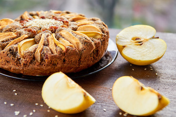 Apple pie with quince, poppy seeds, raisins and sesame on the dark plate decorated with sliced...
