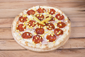 Hot pizza with melting cheese on a rustic wooden table. Delicious meal in the restaurant.