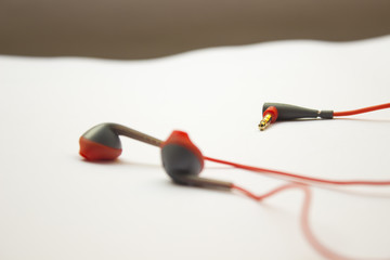 Red earphones on white background. The earphones for using digital music or smart phone. selective focus of earphones.