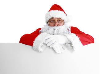 Naklejka premium Happy Santa Claus looking out from behind the blank sign isolated on white background