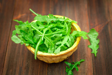 Fresh juicy leaves of arugula on a brown wooden table.