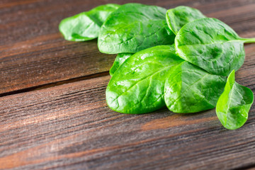Green fresh spinach leaves on a wooden table.