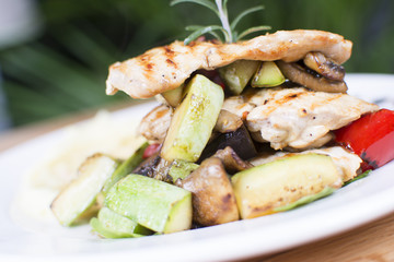 Grill chicken breast. Grilled vegetables with chicken breast. Grilled chicken with vegetables on oak table.