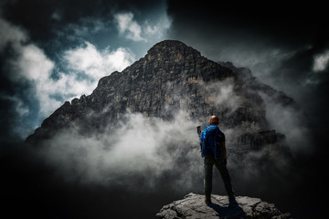 Mountaineer standing below looming dark mountain