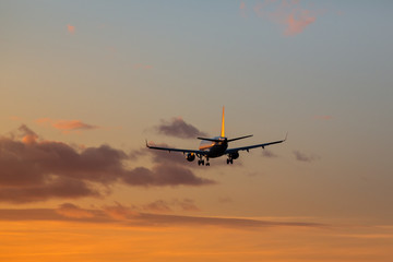 Fototapeta na wymiar Airplane is landing at airport during a wonderful sunset sky background / orange sky