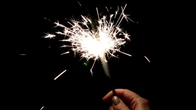 Sparkler enchanting burning in the hand. Lights sparked and burned in his hands. Festive sparklers close - an attribute of good mood.