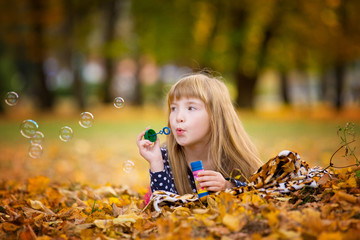 caucasian child girl blowing soap bubbles outdoor at autumn sunset - happy carefree childhood