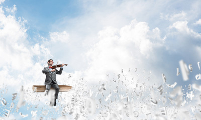 Handsome violinist play his melody and symbols fly around in air