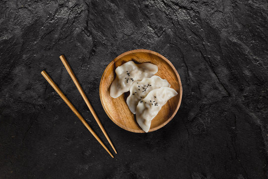 Plate of Asian gyoza dumplings on black slate stone.
