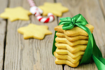 Freshly baked Christmas biscuits wrapped with green ribbon on rustic wooden background