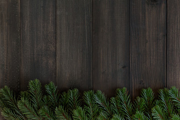Christmas fir tree branches on dark rustic wooden background with copy space for text