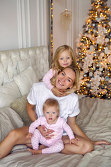 mother with two daughters in their pajamas sitting on the bed in the new year