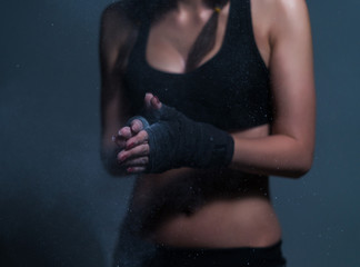 Young fighter boxer fit girl wearing hand bandage preparing before training. She has magnesia in hands