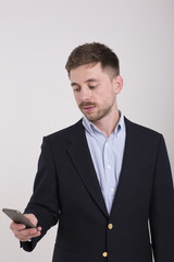 Happy man in black suit typing sms on smartphone