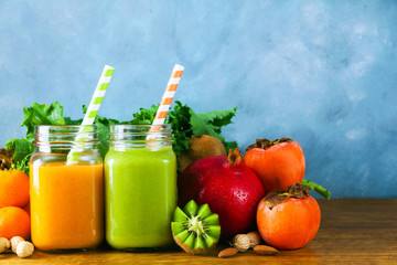 Freshly blended fruit smoothies of various colors and tastes in glass jars in rustic wooden tray. Yellow, green.