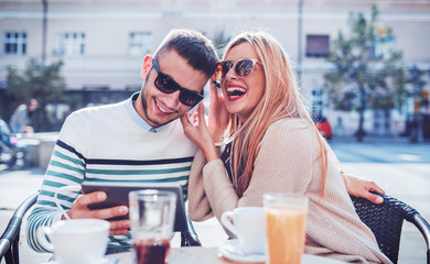 Dating in the cafe. Young couple drinking coffee and listening to music with headphones. Love, dating, technology, lifestyle
