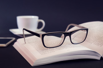 Book  with glass and coffee mug on desk table