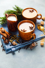 Masala tea chai latte traditional hot Indian teatime ceremony sweet milk with spices, herbs organic infusion healthy beverage in porcelain cup on blue table background