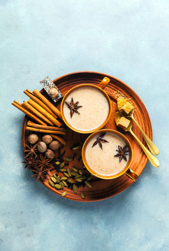 Masala tea chai latte traditional hot Indian teatime ceremony sweet milk with spices, herbs organic infusion healthy beverage in porcelain cup on blue table background