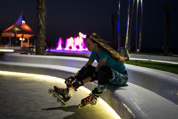 Beautiful caucasian girl enjoys roller skating at night city with lights in bokeh. Outdoor night...