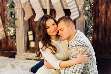 Nice love couple sitting on carpet in front of fireplace. Woman