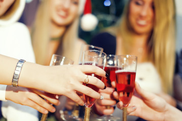 Cheers! Girls friends having xmas party and drinking red shampagne. Toasting with glasses of wine on the smiling womans backgroung. New year party