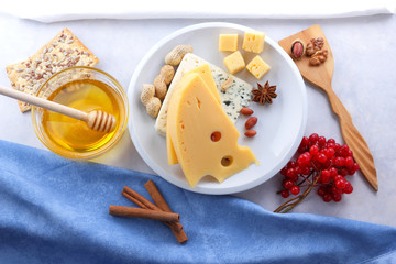 Cheese with mold and hard yellow cheese on a white plate, honey, nuts, red berries on a white background, cheese with holes for Christmas dinner, cheese background, pop art
