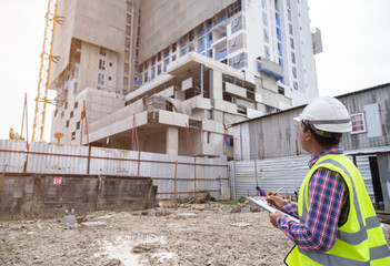 Asian civil engineer checking work for control and management in the construction site or building site of high rise building
