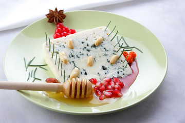 Figure of the Christmas tree with red berries and badyan, Christmas decorations, needles of Christmas tree on white cheese, peanuts, cheese, honey and grains of pomegranate on a green plate, pop art a