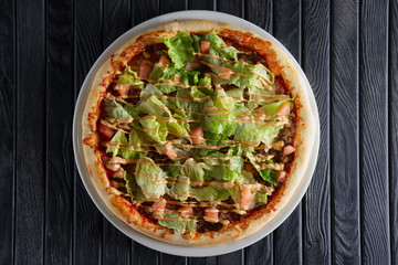 Pizza with ham, mustard sauce and salad leaves