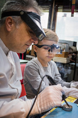 Fototapeta na wymiar Engineering teacher is teaching small boy how to use soldering iron.