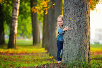 Little girl hugging a tree and smile in park