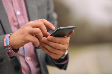 Business man texting on his smart phone outdoors.
