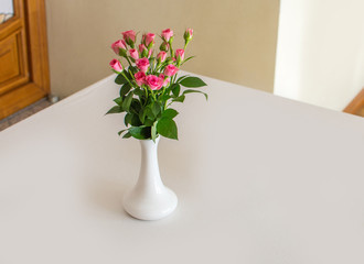 Rose placed in white vase on the desk