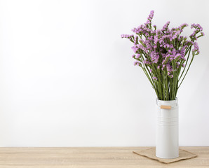 Modern , vintage vase with statice flower and beautiful pink on wood table and white wall background.