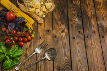 Pasta background. Dry spaghetti with vegetables and herbs on a wooden table. Top view with copy space