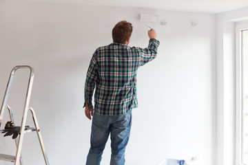 Young man painting a wall on white in a modern home