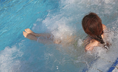 woman during hydromassage sitting in the pool in a luxurious spa