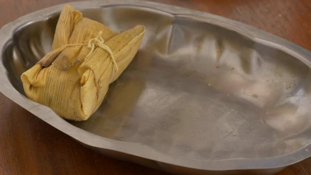 Sideshot shot of a tray been filled with tamales for serving