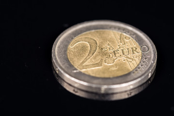 Metal coin of two euros on the black background with reflections